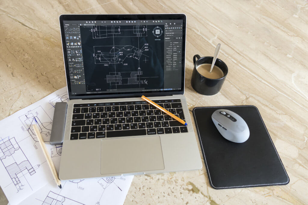 laptop with blueprints mechanical work desk