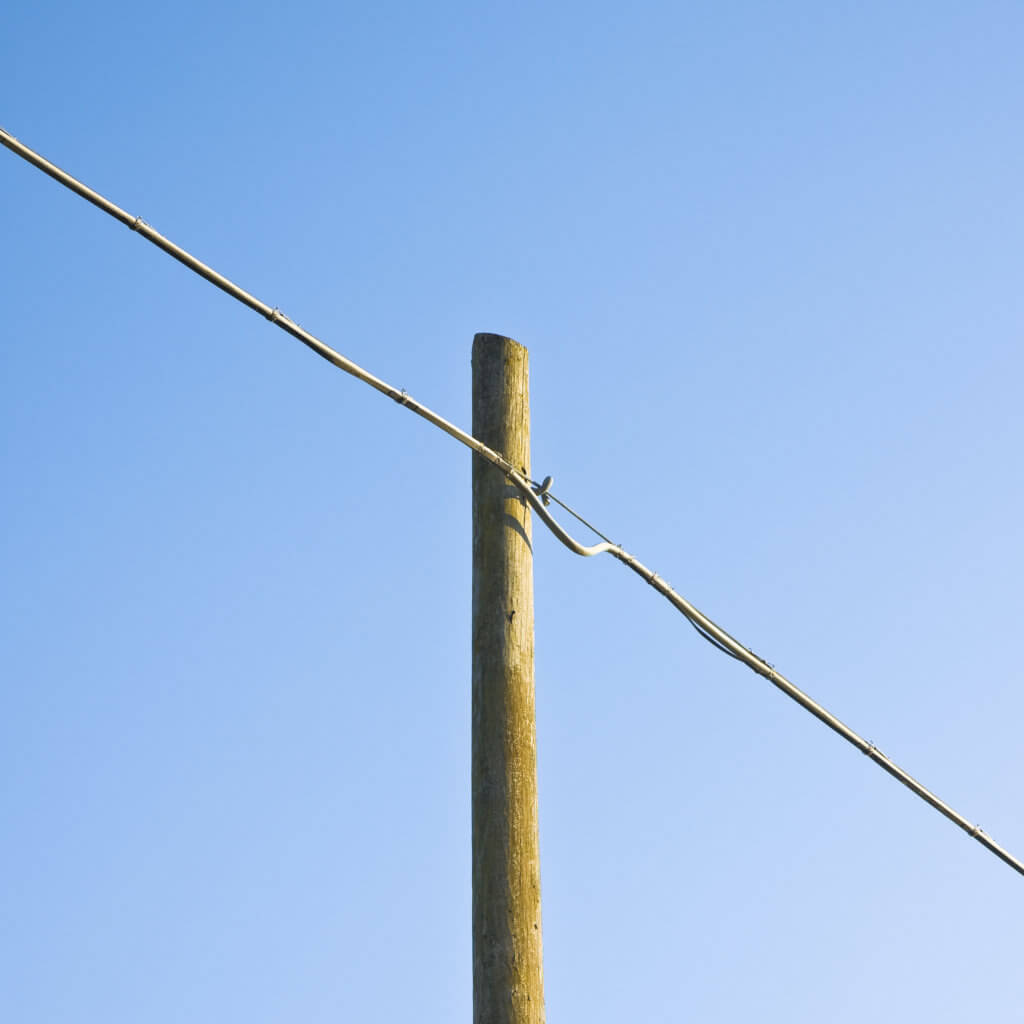 Wooden telephone pole against a blue background